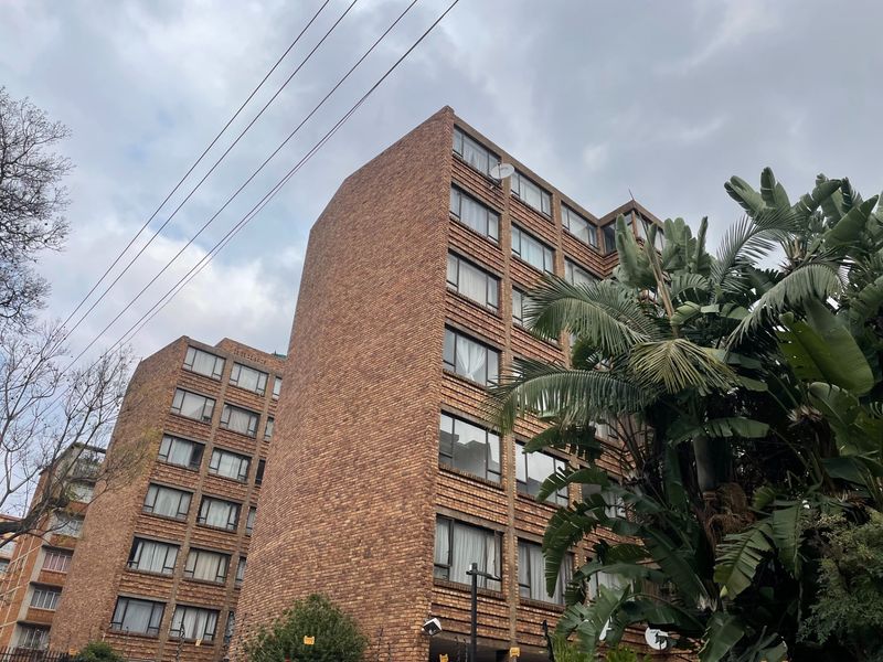 A low-angle view of a multi-story apartment building featuring a classic face brick exterior and aluminum-framed windows.
