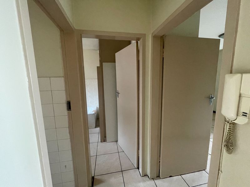 A functional hallway featuring tiled flooring and an intercom system, providing access to multiple rooms within the apartment.