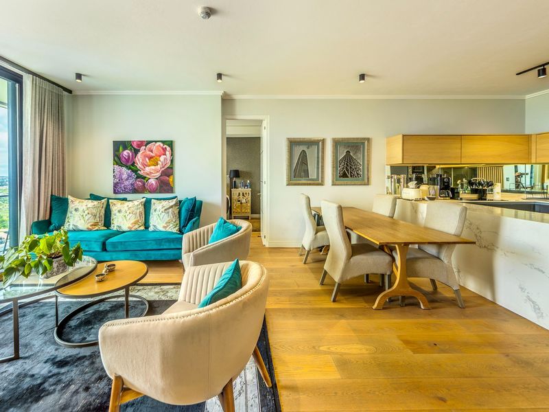Modern open-plan living and dining area featuring engineered wood flooring, a sleek kitchen island with marble-look finish, and expansive floor-to-ceiling windows.