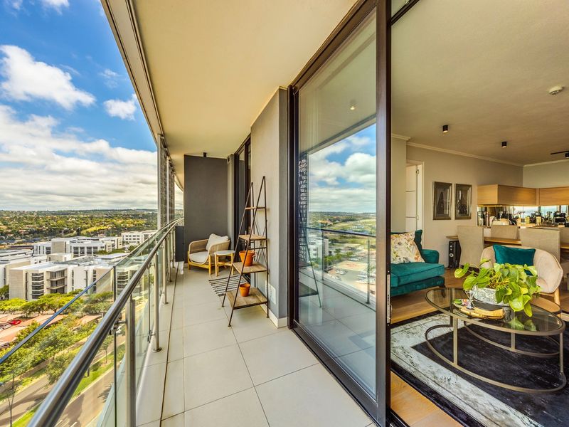 Spacious covered balcony with glass balustrade and sliding door access, offering expansive elevated views and seamless indoor-outdoor flow.