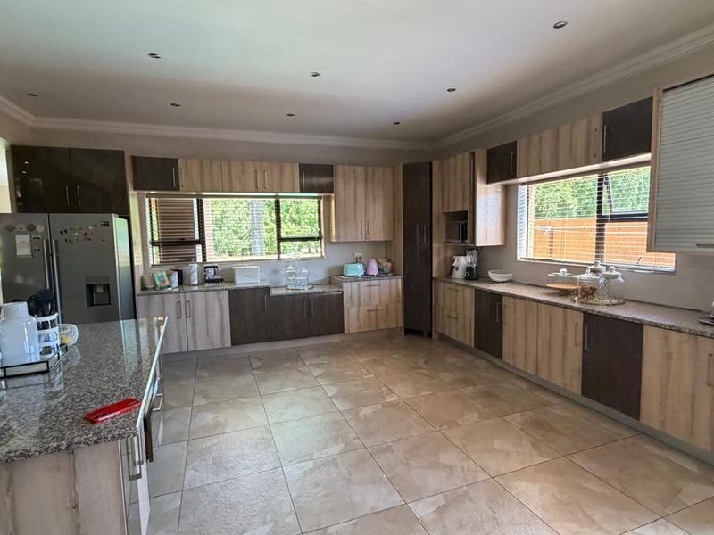 Spacious modern kitchen featuring extensive two-tone cabinetry, granite countertops, recessed lighting, and large windows providing ample natural light.