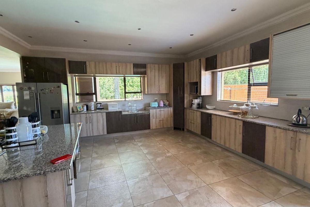 Spacious modern kitchen featuring extensive two-tone cabinetry, granite countertops, recessed lighting, and large windows providing ample natural light.