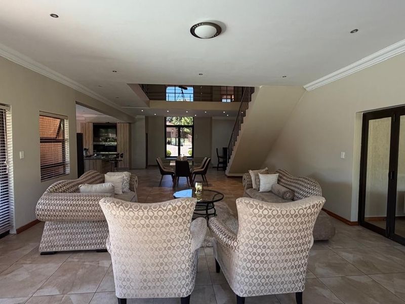 Spacious open-plan living area featuring tiled floors, a staircase, and large sliding glass doors that provide ample natural light.