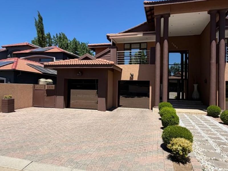 Front elevation of a modern double-story house featuring a paved driveway, double garage, and a covered entrance with architectural pillars.