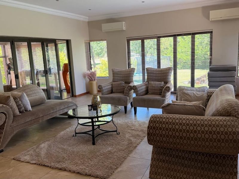 Spacious living room featuring tiled flooring, recessed lighting, dual split-system air conditioning units, and large aluminium sliding doors providing ample natural light.