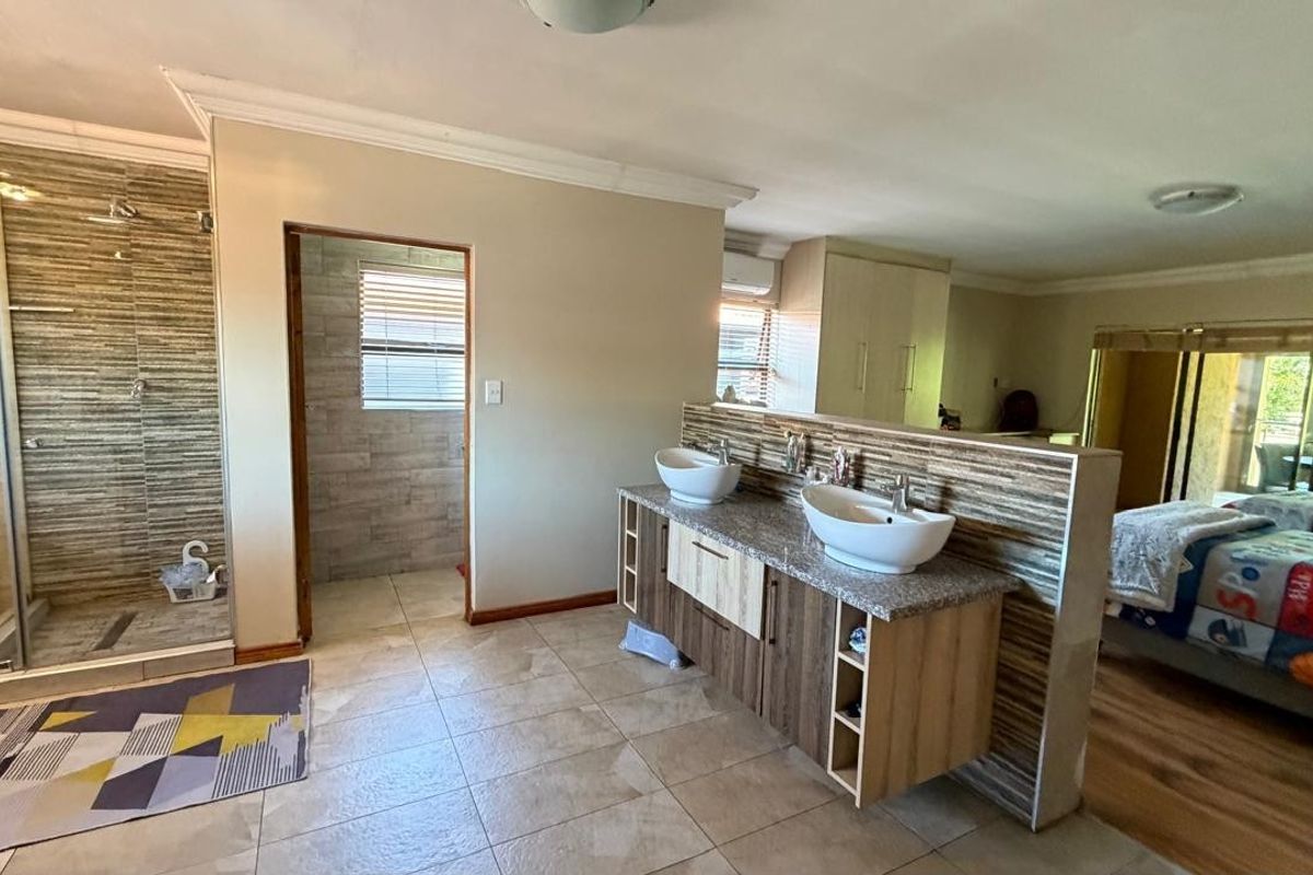 Spacious bedroom featuring an open-plan en-suite bathroom with a double vanity, vessel sinks, and a separate walk-in shower area.