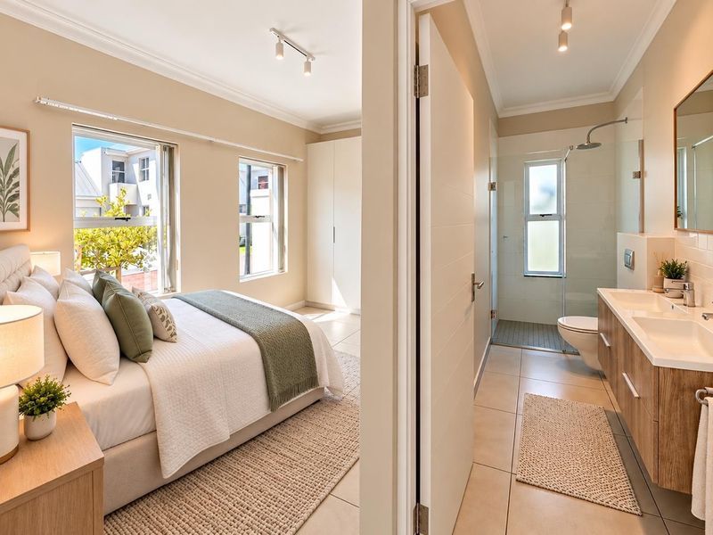 A well-appointed bedroom featuring built-in cupboards and an en-suite bathroom with a modern double vanity, glass shower, and wall-mounted toilet.