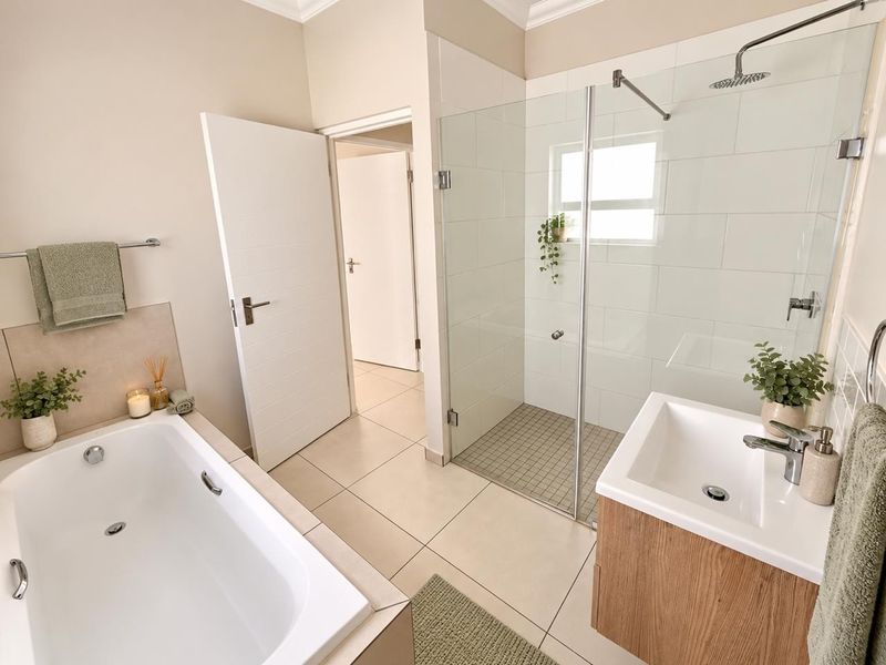 Modern bathroom featuring a built-in bathtub, a spacious glass-enclosed shower with a rain shower head, and a contemporary vanity unit.