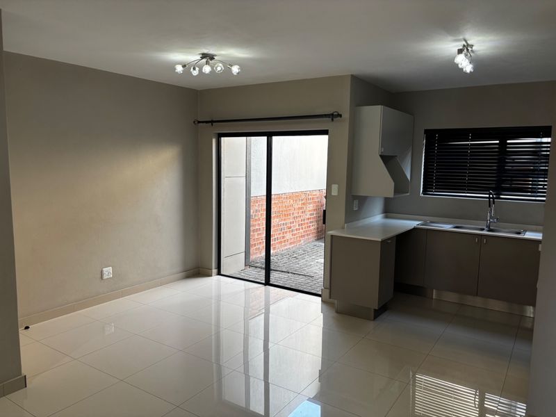 An open-plan living and kitchen area featuring polished tiled floors, modern cabinetry, and a sliding door providing access to an outdoor space.