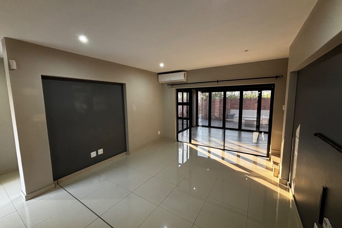 Spacious, modern living area featuring large format floor tiles, a feature wall, and sliding glass doors providing seamless access to the outdoor patio.