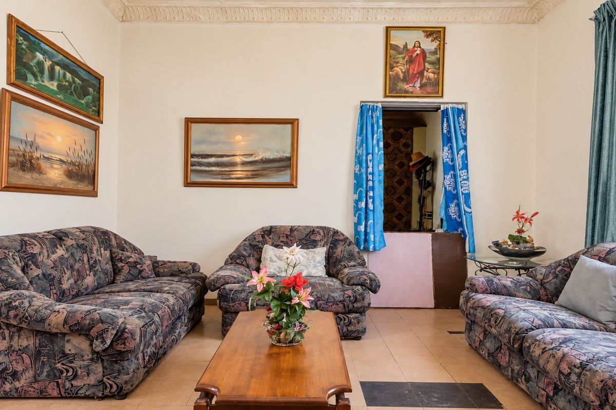 A living room featuring tiled flooring and ornate ceiling cornicing, offering a traditional layout with potential for modernization.