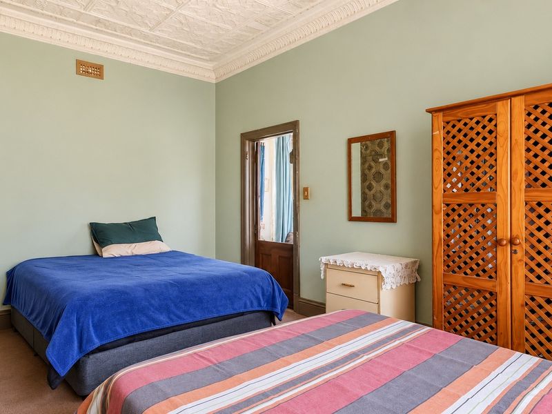 Spacious bedroom featuring a classic ornate pressed metal ceiling, decorative cornice, and neutral wall tones, offering a traditional architectural aesthetic.