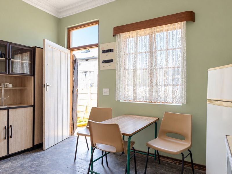 A functional kitchen area featuring built-in cabinetry, a timber-framed window, and direct access to the exterior.