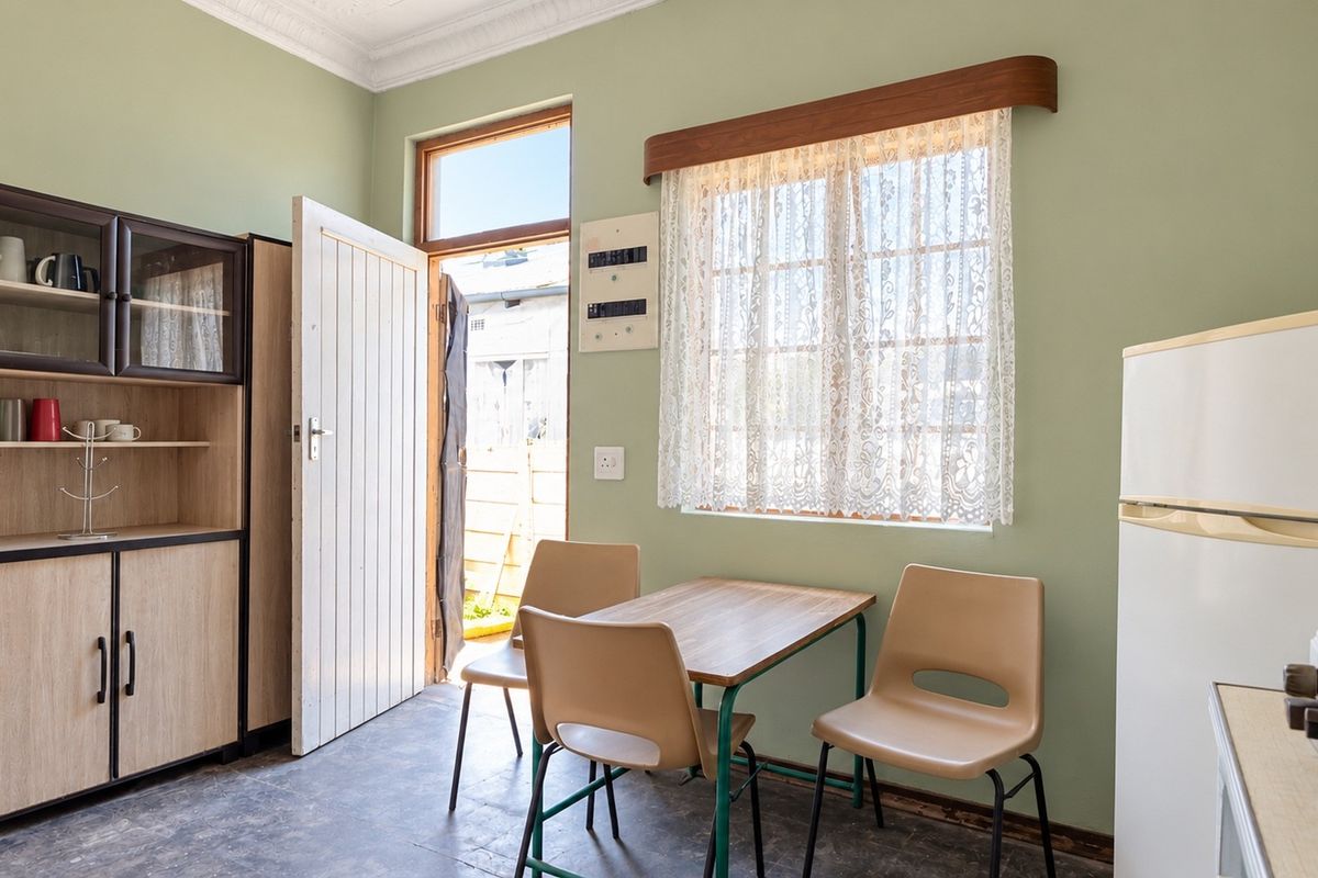 A functional kitchen area featuring built-in cabinetry, a timber-framed window, and direct access to the exterior.