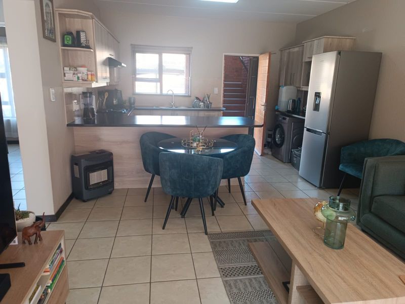 Open plan living and kitchen area featuring tiled flooring, built-in cabinetry with laminate countertops, and a breakfast bar counter.