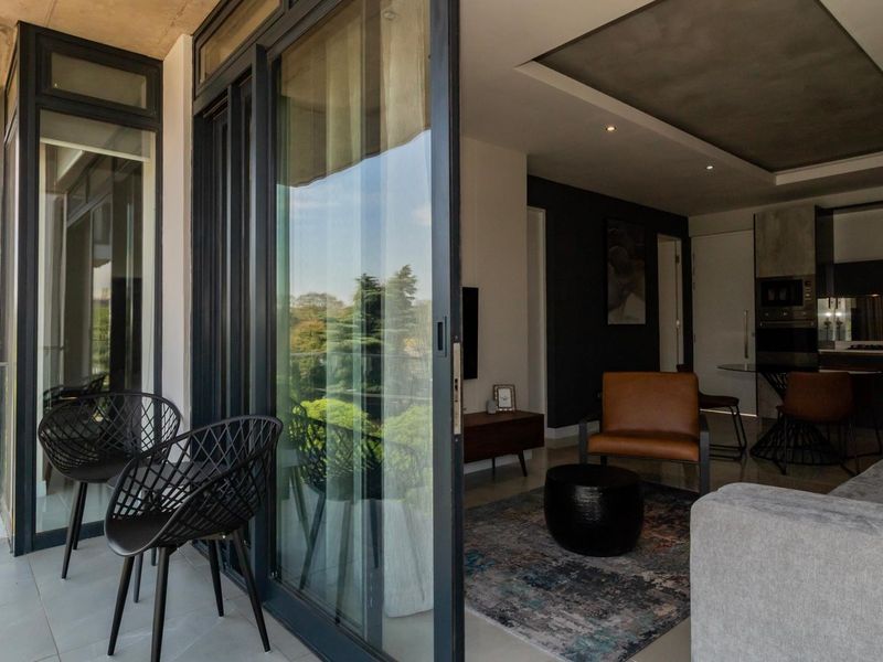Modern open-plan living area featuring seamless indoor-outdoor flow to a private balcony with glass balustrades and contemporary kitchen finishes.