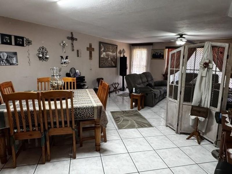 An open-plan living and dining area featuring tiled flooring and a ceiling fan, offering a functional layout for family living.