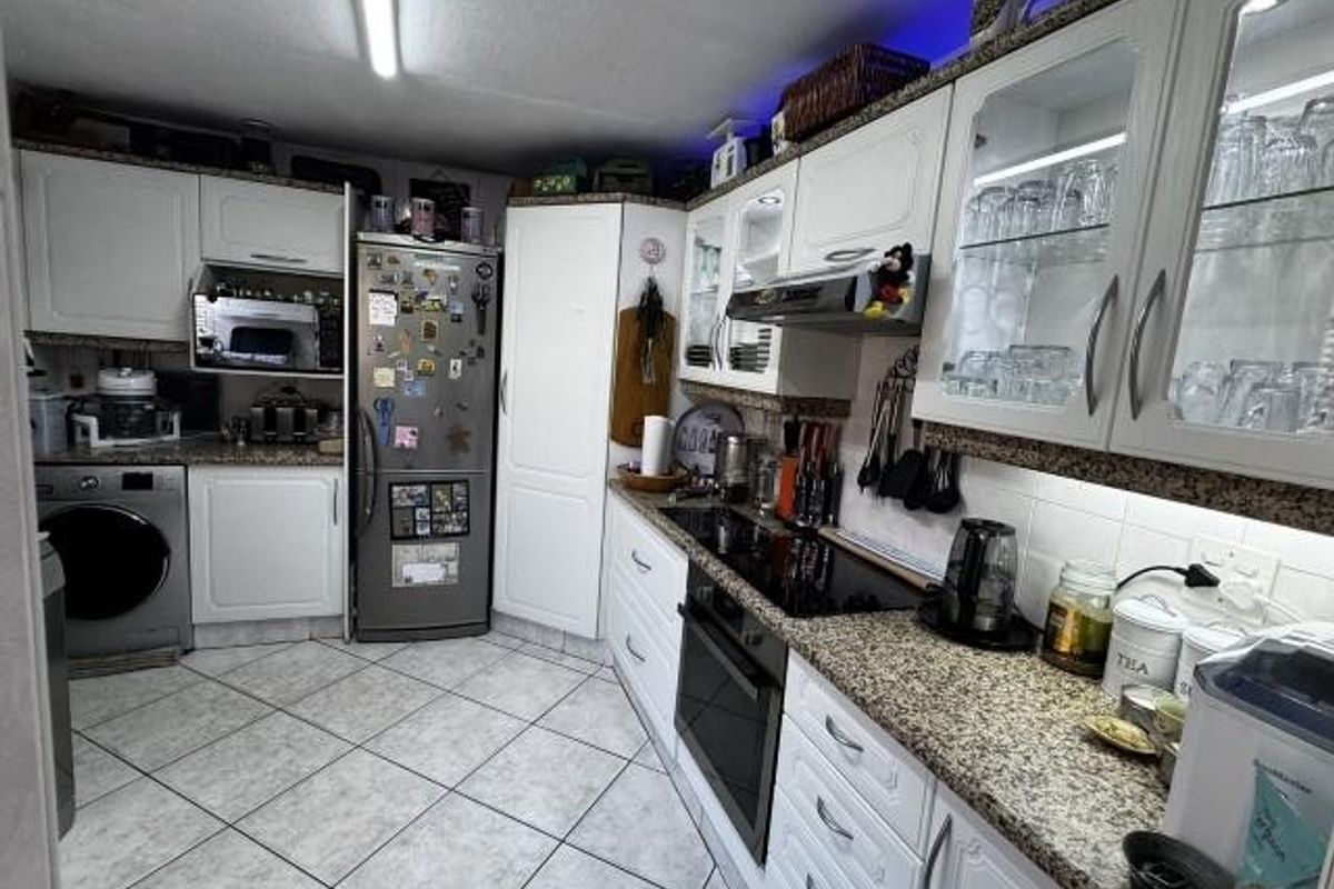 A functional kitchen featuring white cabinetry, granite countertops, built-in appliances, and tiled flooring with integrated lighting.