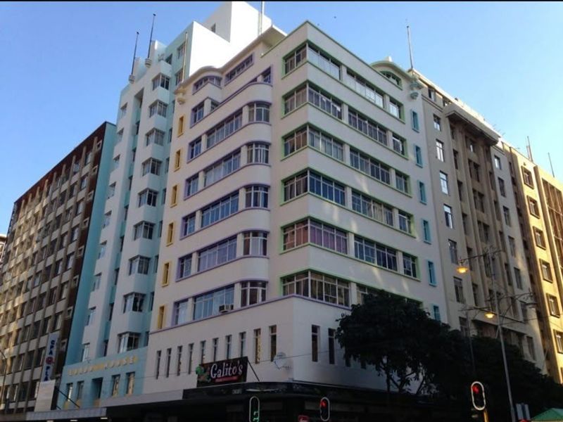 A multi-story commercial office building featuring a distinctive architectural facade with large windows and prominent corner positioning in an urban setting.