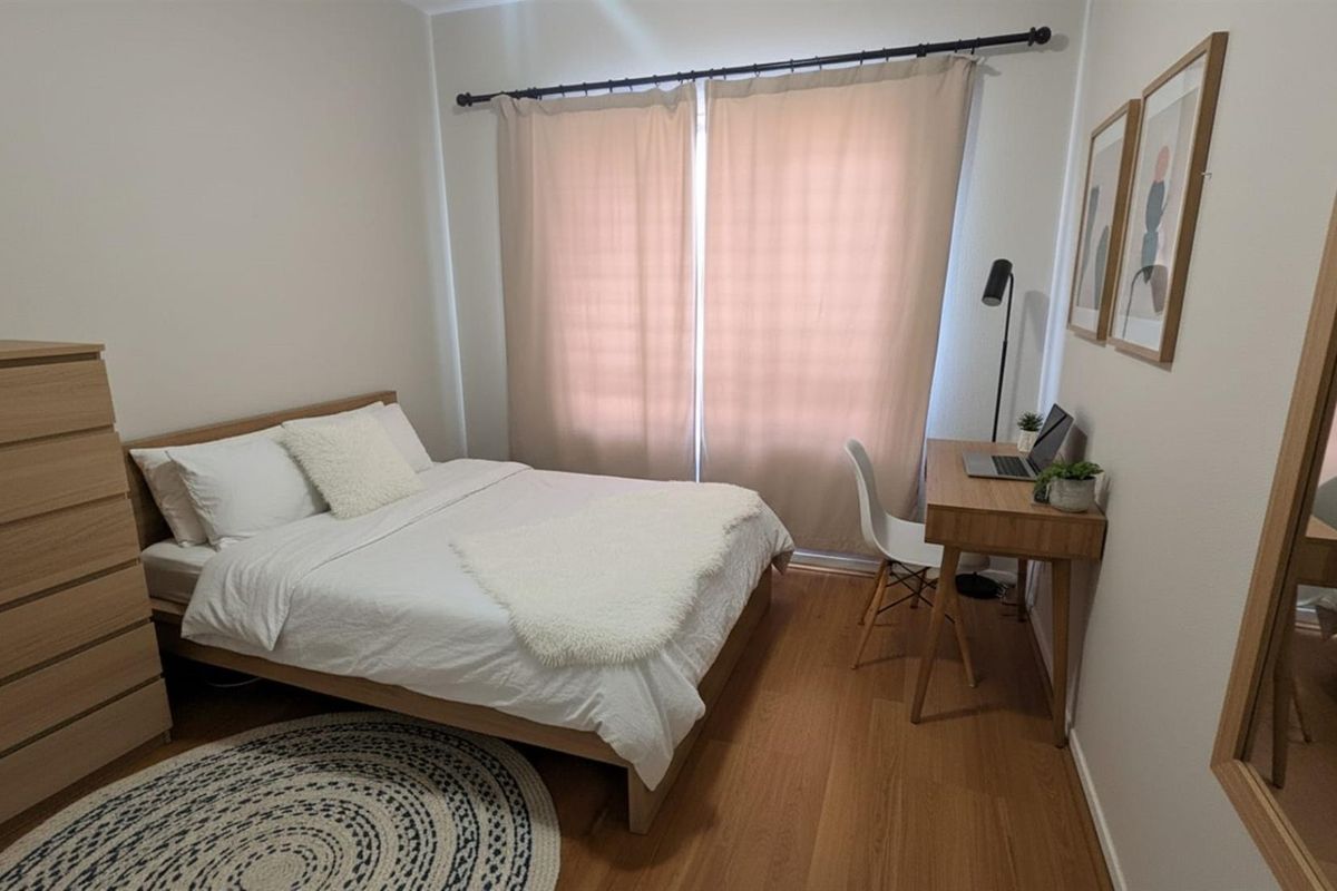 A well-maintained bedroom featuring laminate flooring and neutral wall finishes, providing a comfortable and functional living space.
