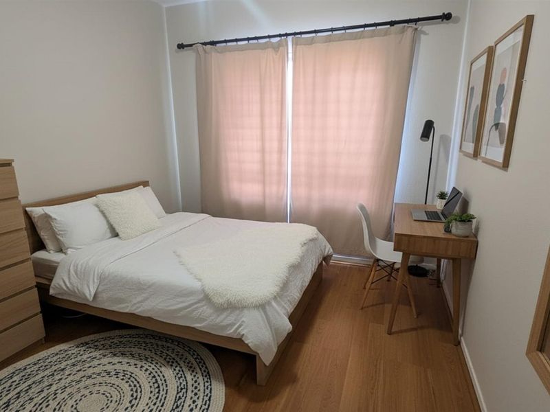 A well-maintained bedroom featuring laminate flooring and neutral wall finishes, providing a comfortable and functional living space.