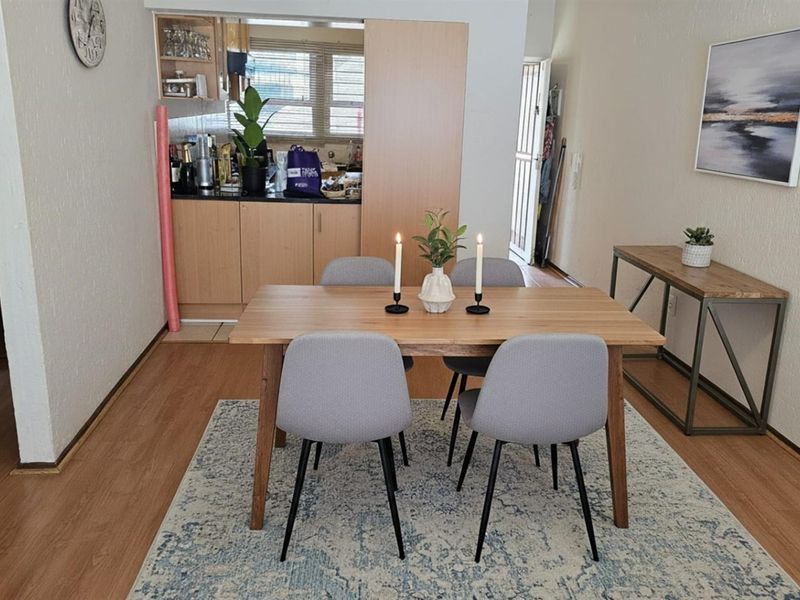 Open plan dining area adjacent to a functional kitchen with built-in cabinetry and laminate flooring throughout.