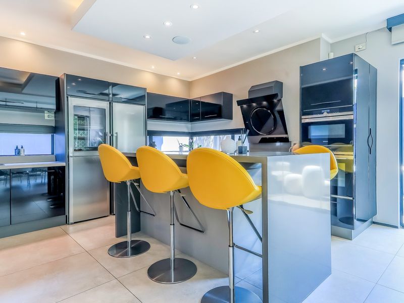 Modern kitchen featuring high-gloss cabinetry, a central island with breakfast bar, integrated appliances, and recessed ceiling lighting.