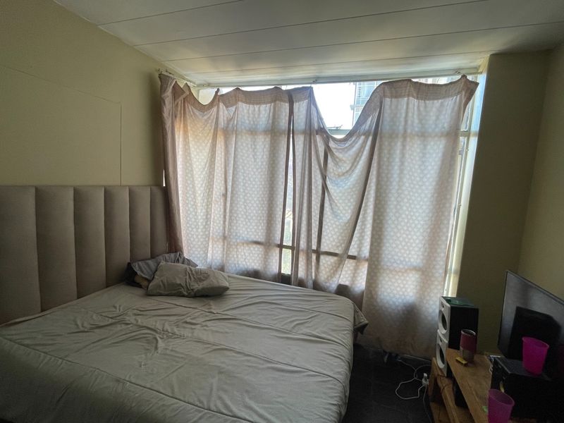 A bedroom featuring a large window with natural light and tiled flooring, offering a blank canvas for potential interior updates and modernization.