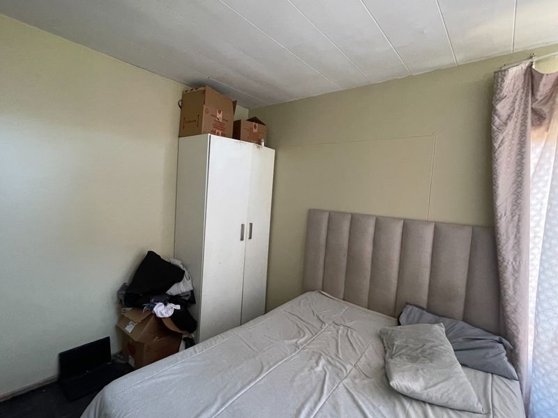 A bedroom featuring a built-in wardrobe and a panelled ceiling, offering a functional space ready for personal touches.