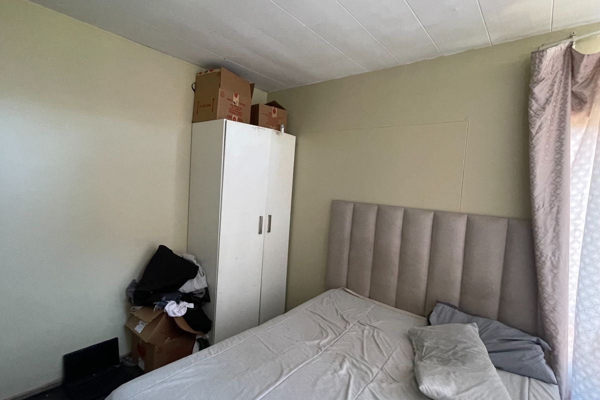 A bedroom featuring a built-in wardrobe and a panelled ceiling, offering a functional space ready for personal touches.