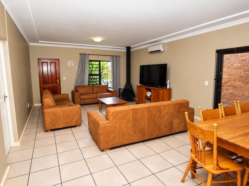 Spacious open-plan living and dining area featuring tiled flooring, a freestanding fireplace, and a wall-mounted air conditioning unit.
