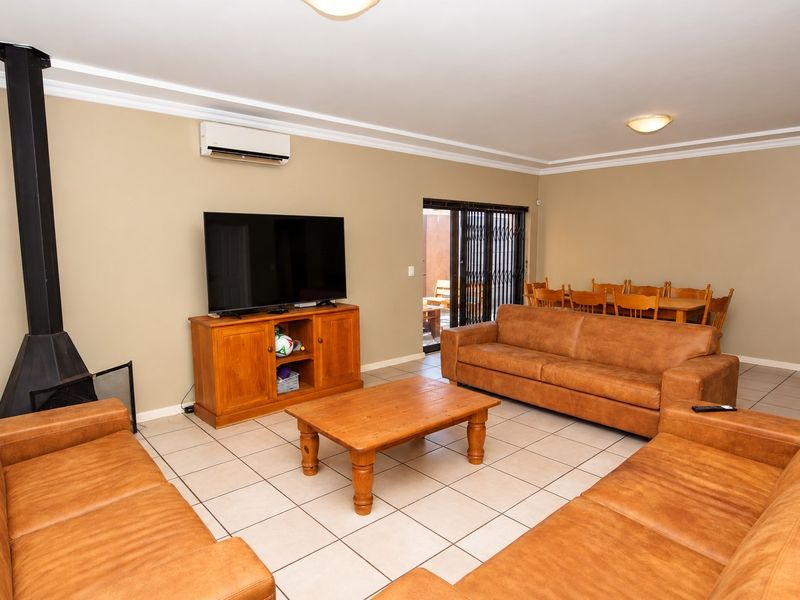 Spacious living area featuring tiled flooring, a freestanding fireplace, and a wall-mounted air conditioning unit, with direct access to an outdoor patio area.