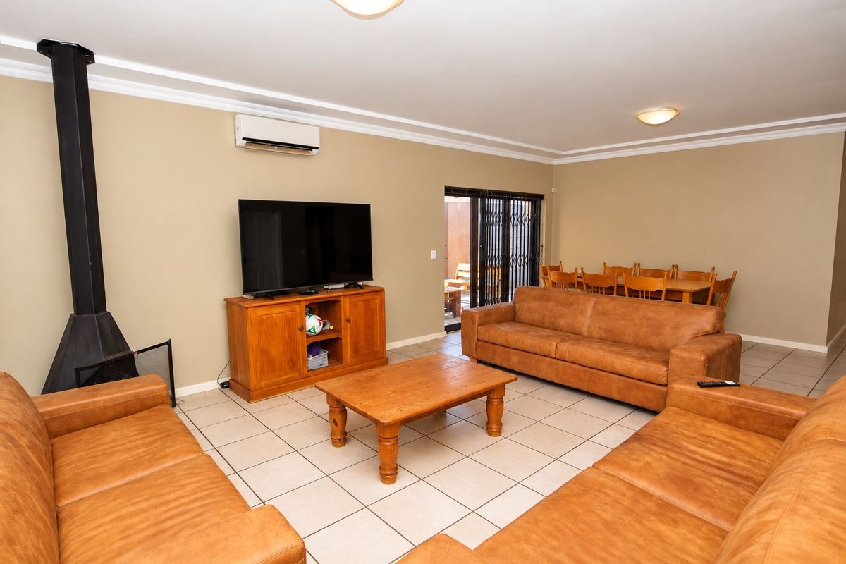 Spacious living area featuring tiled flooring, a freestanding fireplace, and a wall-mounted air conditioning unit, with direct access to an outdoor patio area.
