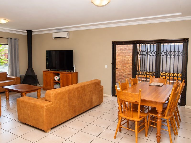 Open-plan living and dining area featuring tiled flooring, a freestanding fireplace, and a split-system air conditioner with direct access to an outdoor space.