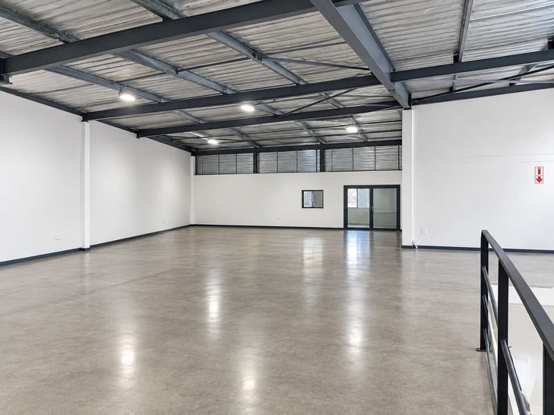 Spacious industrial open-plan area featuring polished concrete floors, exposed steel roof structure, and high-level windows providing ample natural light.