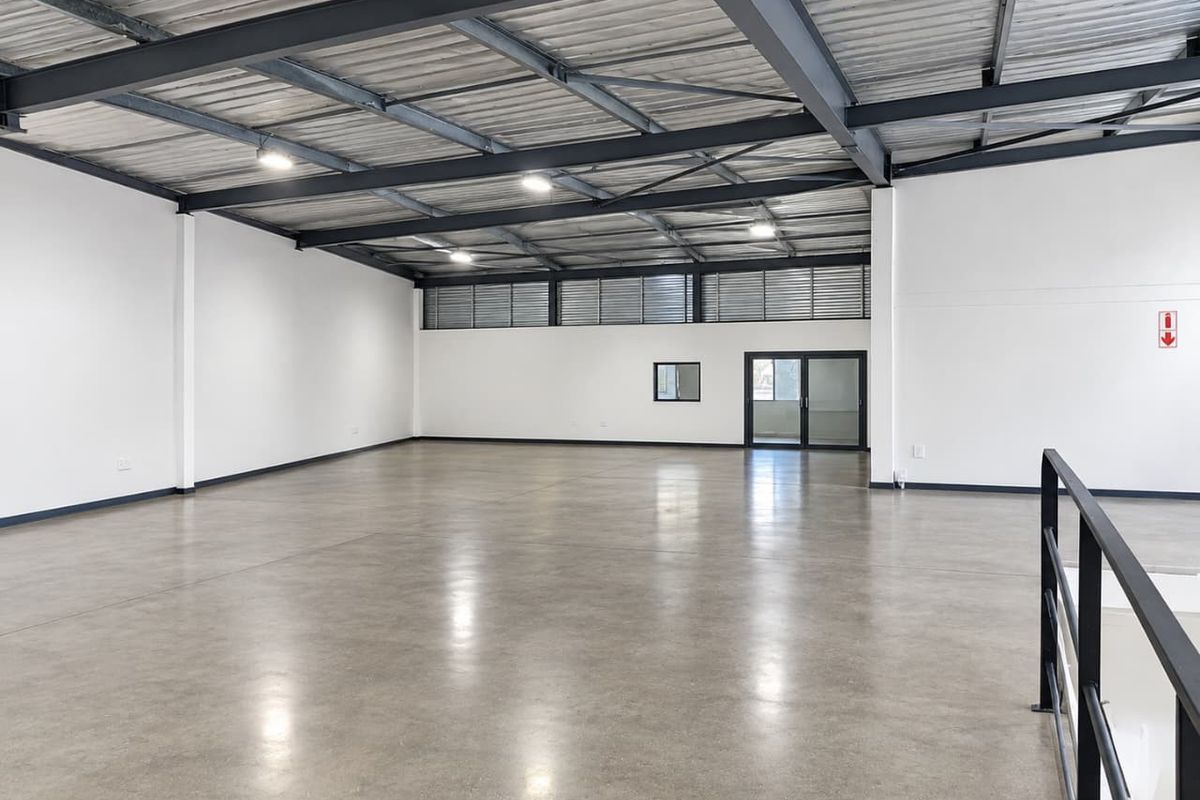 Spacious industrial open-plan area featuring polished concrete floors, exposed steel roof structure, and high-level windows providing ample natural light.