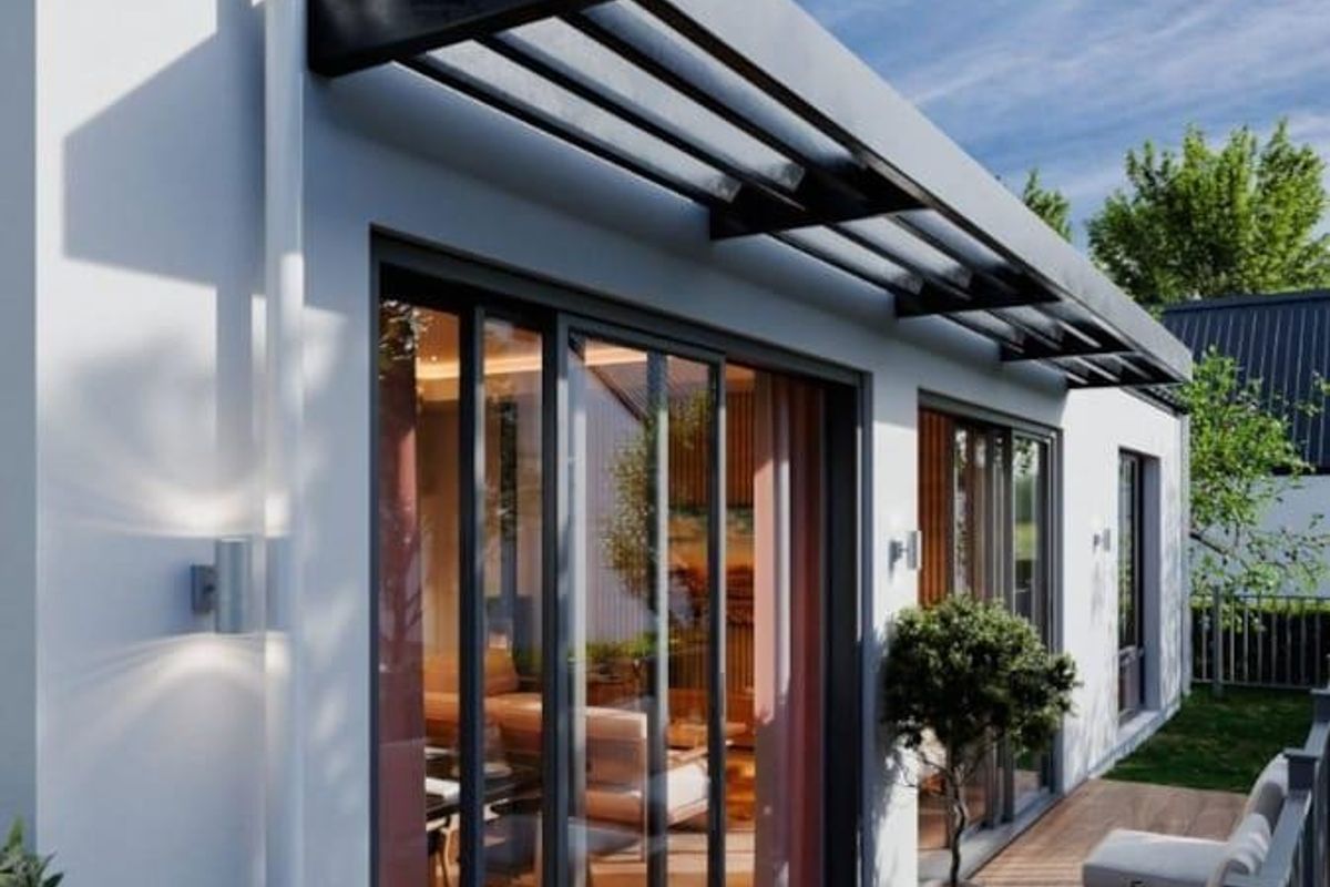 A modern, well-maintained timber deck patio featuring a fixed overhead canopy, sliding glass doors, and contemporary exterior lighting.
