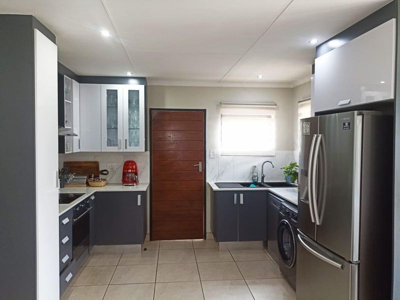 Modern kitchen featuring sleek two-tone cabinetry, stone countertops, integrated appliances, and tiled flooring, offering a clean and functional culinary space.