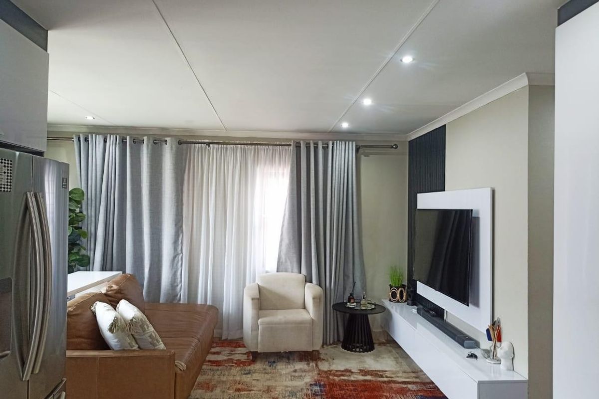 A well-maintained living room featuring recessed downlighting, a modern built-in media console, and a decorative feature wall panel.