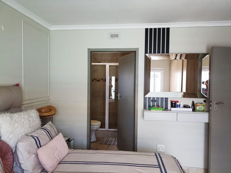 Bedroom featuring a built-in vanity unit with mirror and direct access to an en-suite bathroom with tiled finishes.