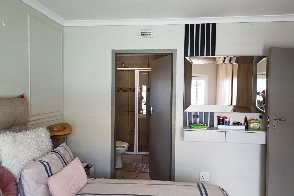 Bedroom featuring a built-in vanity unit with mirror and direct access to an en-suite bathroom with tiled finishes.