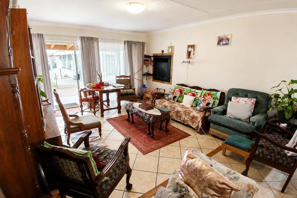 A spacious living room featuring tiled flooring and a sliding glass door providing access to the outdoor patio area.
