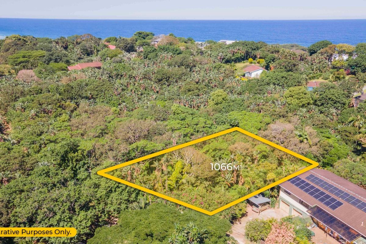 An aerial view of a 1066m2 vacant residential plot surrounded by lush coastal vegetation with ocean views in the background.