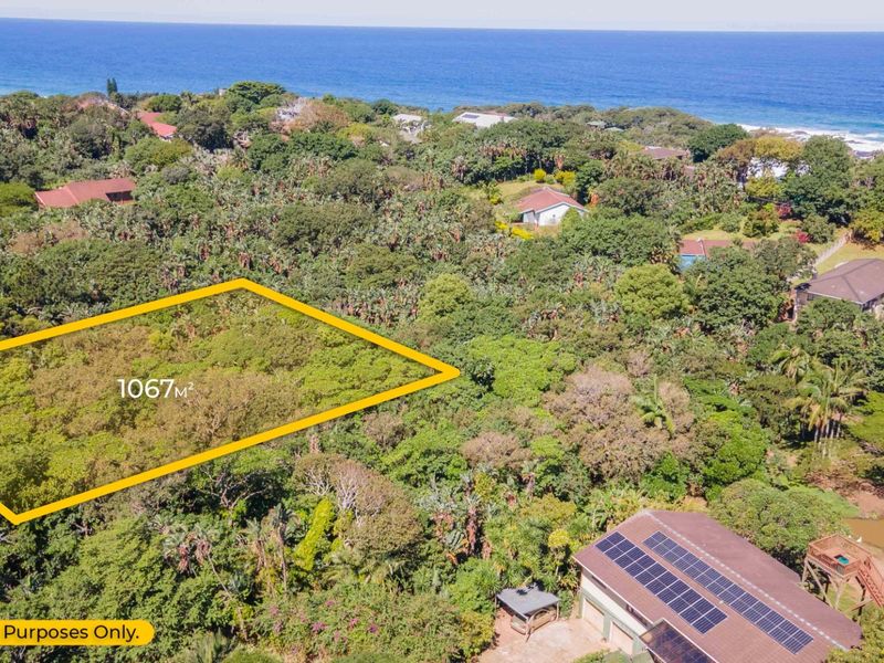 Aerial view of a 1067m2 vacant residential plot situated in a lush coastal area with ocean views.