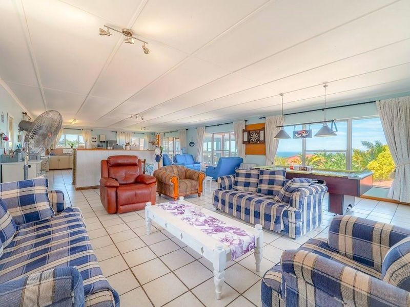 Spacious open-plan living and kitchen area featuring tiled flooring, large windows with scenic views, and ample natural light throughout the living space.