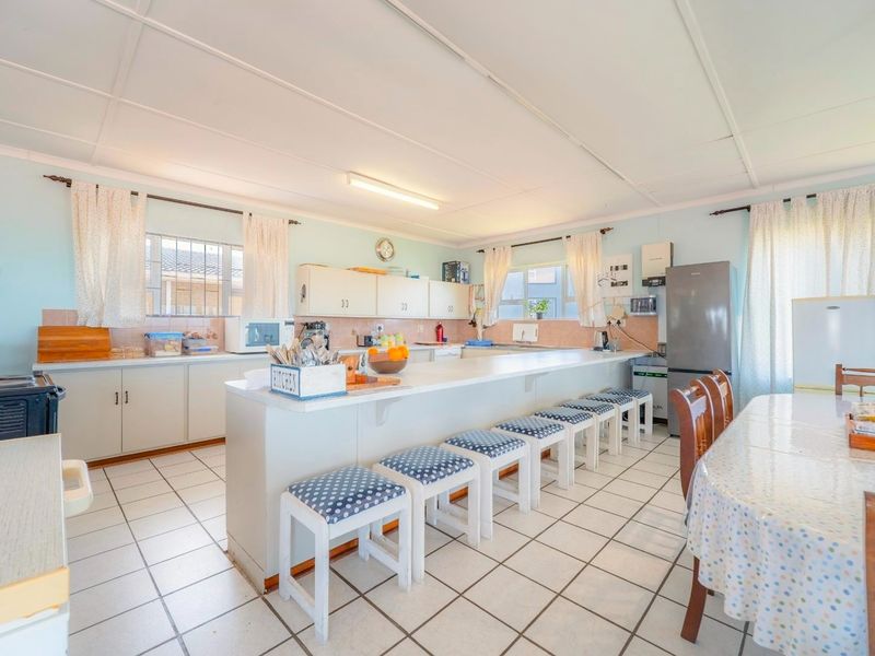 Spacious open-plan kitchen featuring a large central island with breakfast bar seating, tiled flooring, and ample built-in cabinetry.