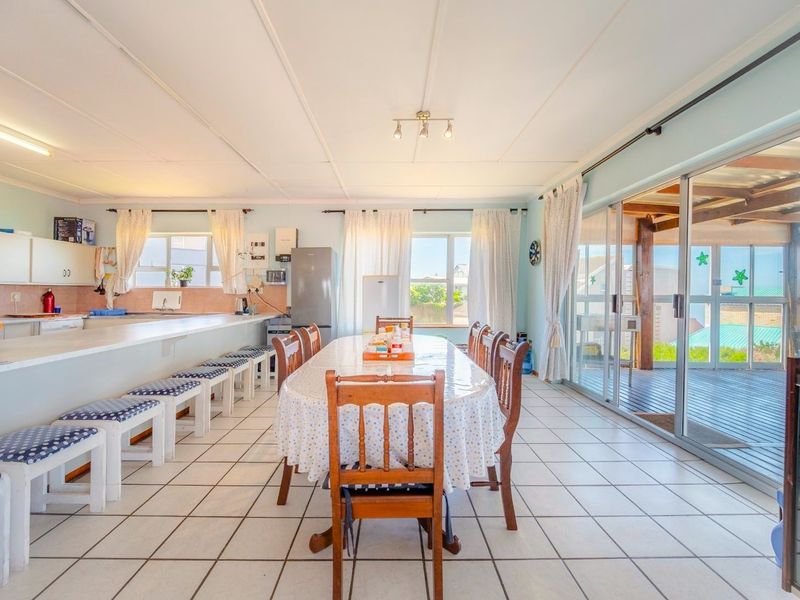 Spacious open-plan kitchen and dining area featuring tiled flooring, a breakfast bar, and large sliding doors leading to an outdoor patio.