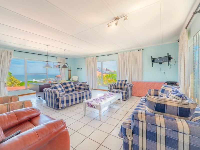 Spacious living area featuring tiled flooring, large windows with ocean views, and a wall-mounted television bracket.