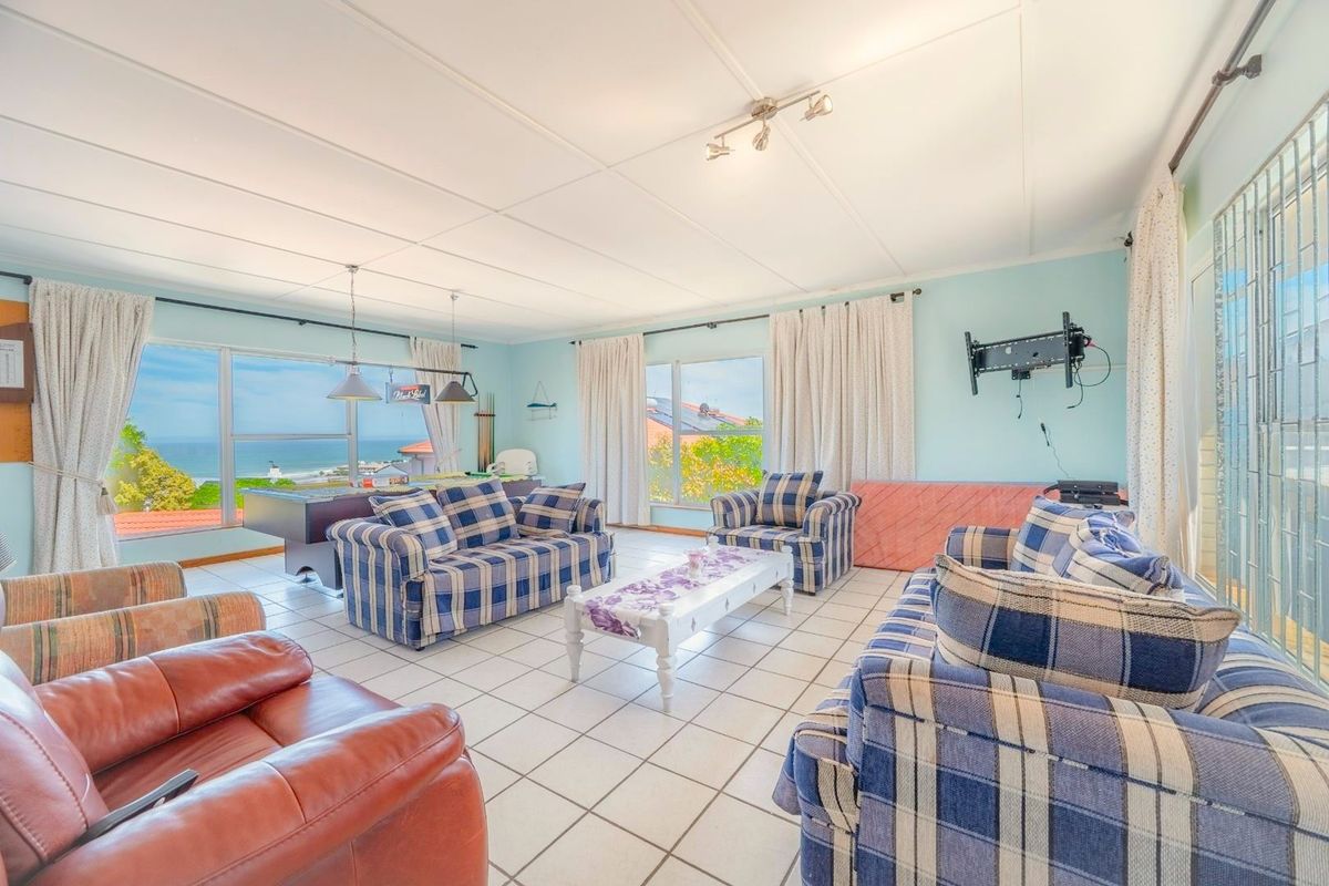 Spacious living area featuring tiled flooring, large windows with ocean views, and a wall-mounted television bracket.