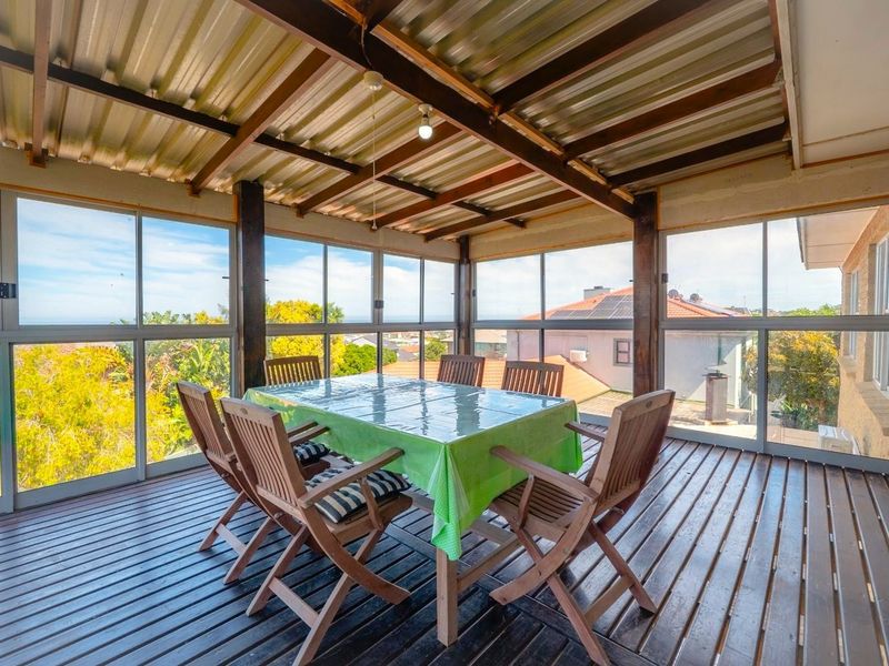 Enclosed patio area featuring timber decking, exposed timber beams, and large aluminium-framed windows offering elevated views.